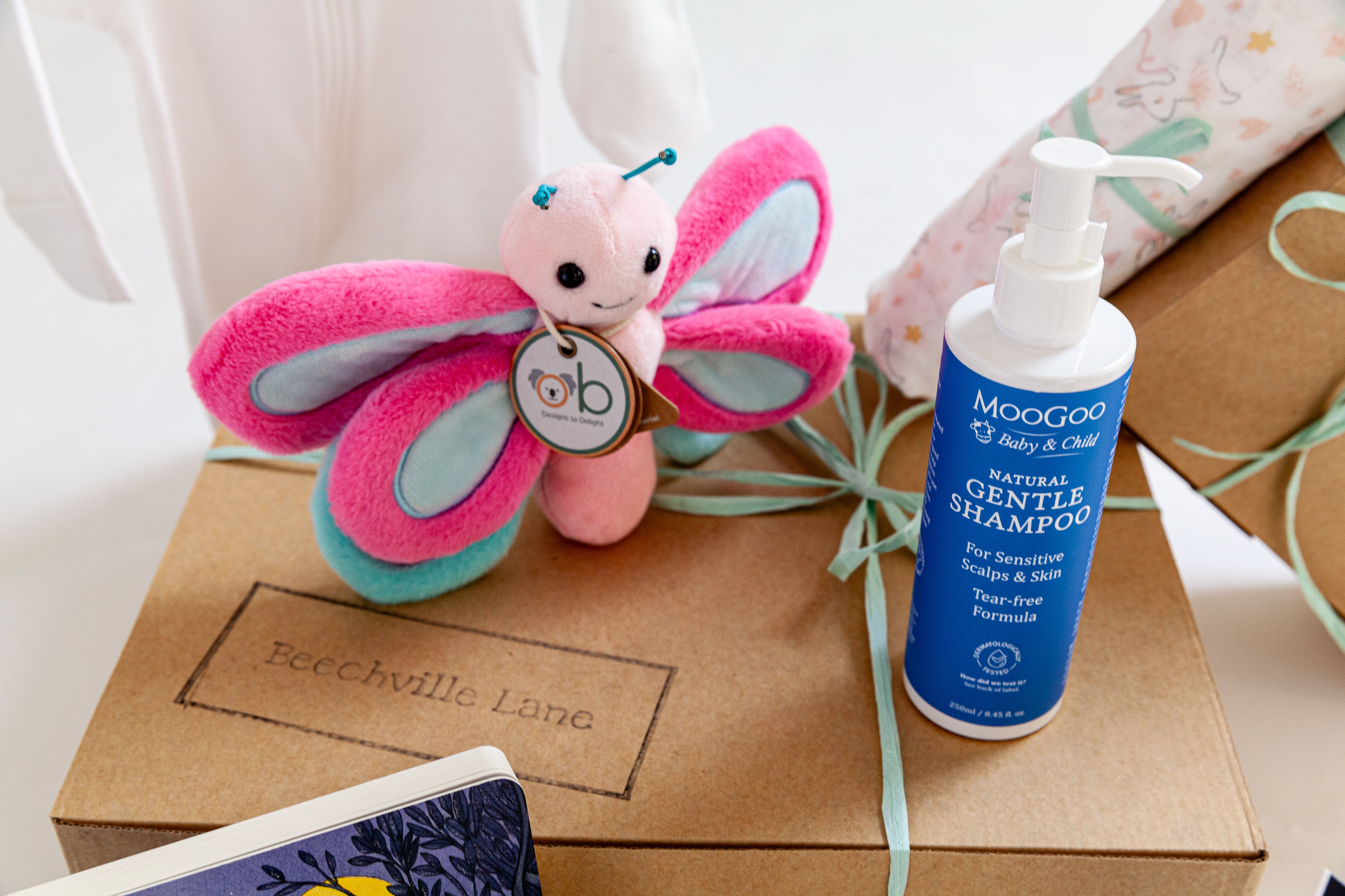Butterfly plush toy and bottle of Moogoo natural gentle shampoo on a box with Beechville Lane branding. Corporate maternity gift hamper Australia, perfect for a new baby and mum, dad.