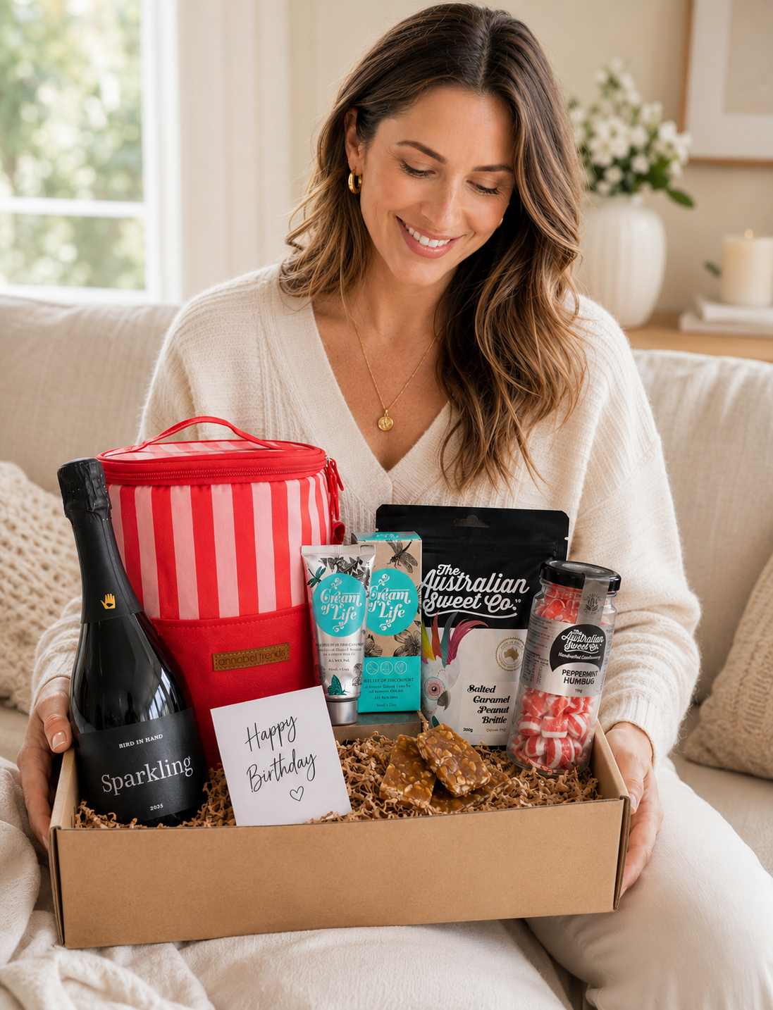 Women with gift hamper, sparkling wine, cooler bag, hand cream and treats. Perfect gift for her hamper