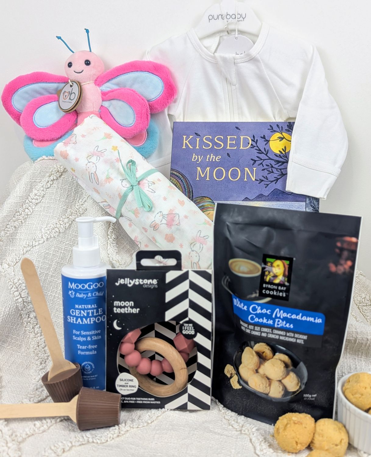 Collection of baby products including a butterfly toy, teether, and cookies in a new mum and new baby gift box. Best new mum hamper Australia. New baby hamper. Corporate maternity gift hamper Australia wide.